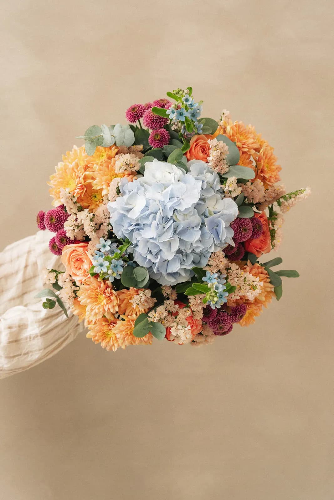 Bouquet orange, bleu et blanc tenu dans les mains